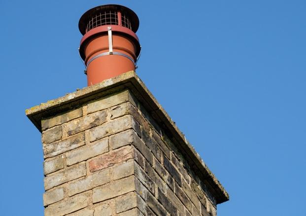 Professional chimney cowl installation on brick chimney stack showing proper fitting and weather protection for improved chimney performance