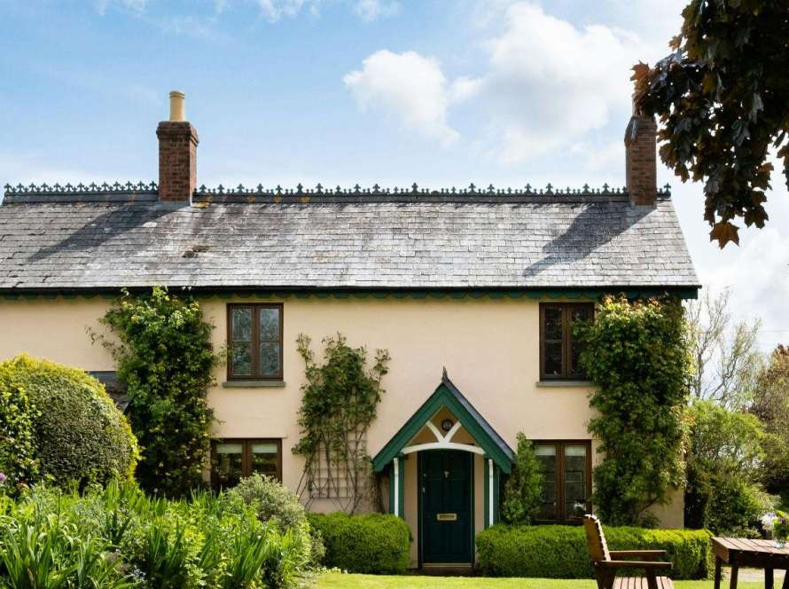 Traditional Cambridgeshire cottage with twin brick chimney stacks in summer garden, showing typical property requiring professional chimney inspection before autumn heating season