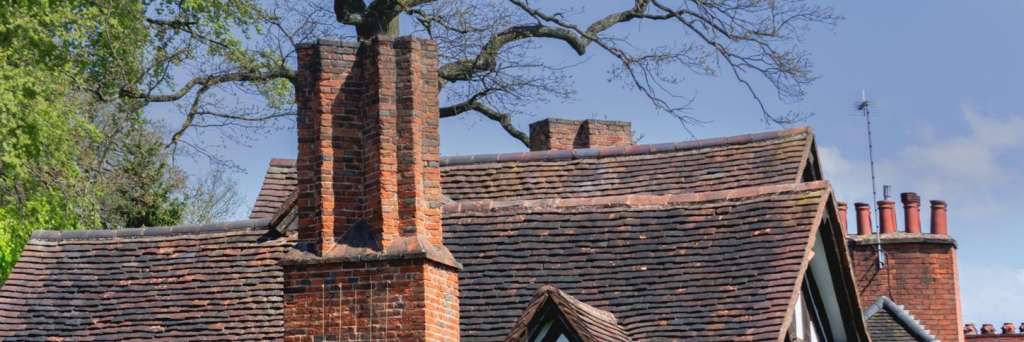 Tudor period house with multiple brick chimney stacks in Cambridge area, showing traditional properties requiring certified Guild of Master Chimney Sweeps professional services