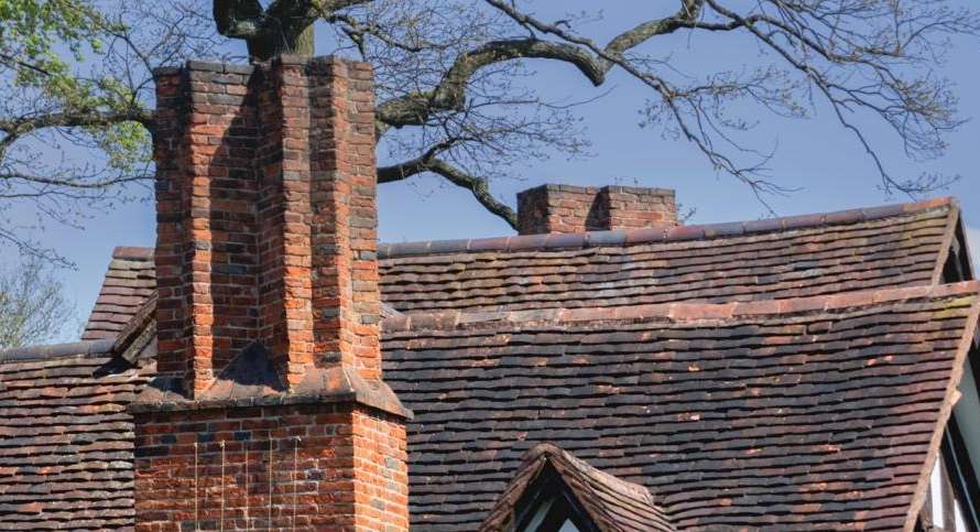 Tudor period house with multiple brick chimney stacks in Cambridge area, showing traditional properties requiring certified Guild of Master Chimney Sweeps professional services
