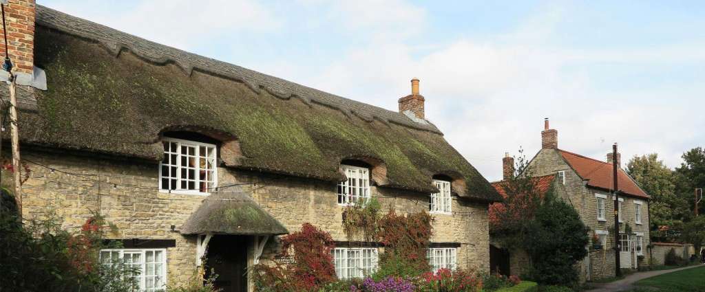 Traditional thatched cottage village in Cambridgeshire with brick chimney stacks, showing typical properties where first fire safety preparation is essential for seasonal heating