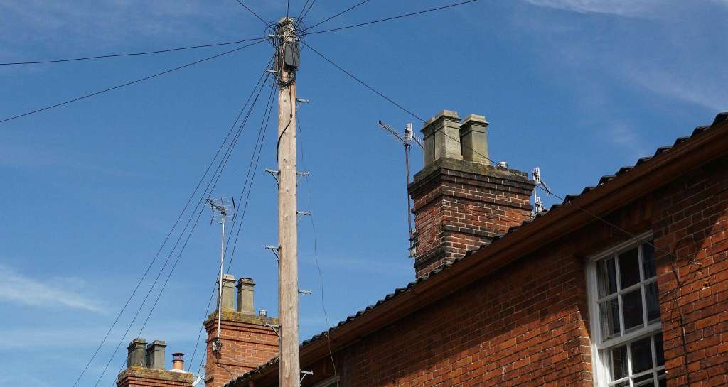 Traditional red brick Victorian terraced houses in Cambridge showing multiple chimney stacks against blue sky, typical of properties requiring professional chimney maintenance