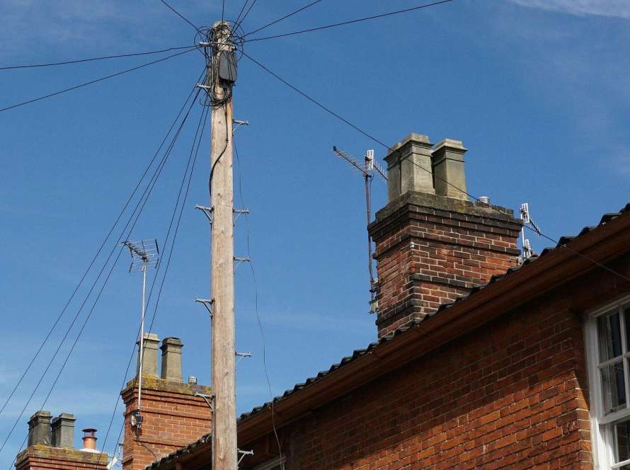 Traditional red brick Victorian terraced houses in Cambridge showing multiple chimney stacks against blue sky, typical of properties requiring professional chimney maintenance
