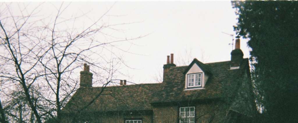 Traditional Cambridge area stone cottage with multiple brick chimney stacks, showing typical property where professional chimney sweeping improves heating efficiency and reduces energy bills