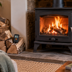 Wood-burning stove with a controlled fire, dry logs and a moisture meter beside the hearth